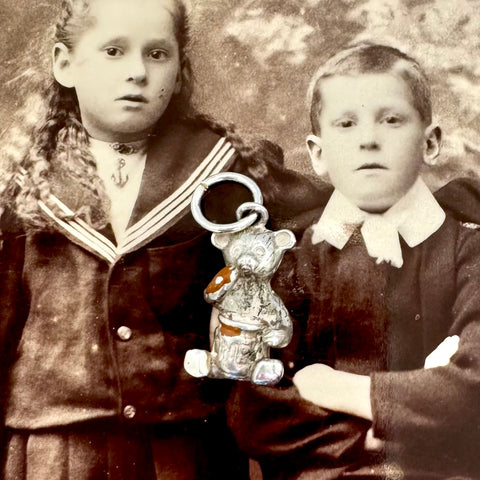 Vintage silver bear eating honey charm on an antique photo of children.