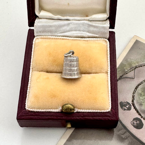 Vintage silver thimble charm in a jewellery box with a vintage photo in the background
