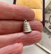 Small vintage silver thimble charm held between fingers with a neutral background