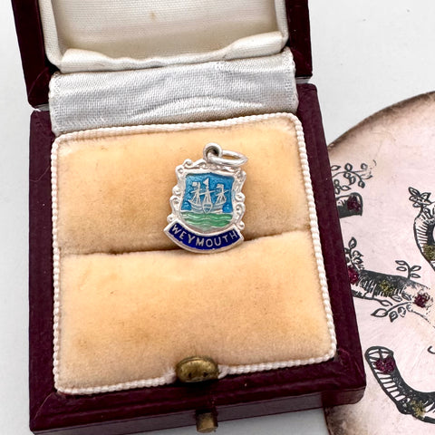 Silver and blue enamel charm with 'Weymouth' text in a velvet-lined box.