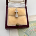Vintage silver wishing well charm in an open jewelry box on a textured surface