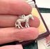 Silver zebra charm held between fingers with a jewelry box in the background