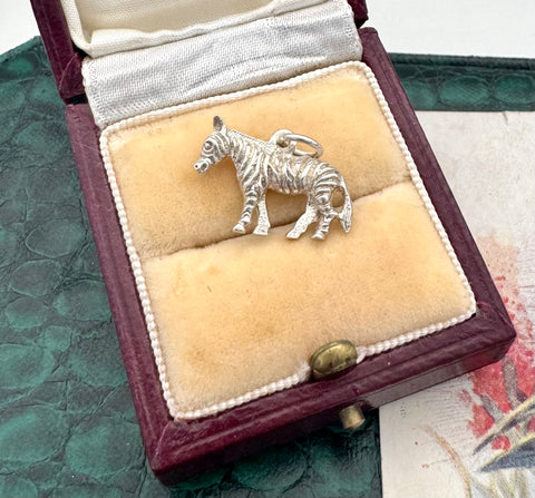 Silver zebra charm in a jewelry box on a textured surface