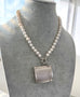 Vintage 1935 hallmarked vesta case made by G&SC Ltd of Regent St, London on a pearl necklace on a grey mannequin