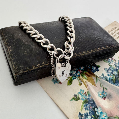 Vintage 1963 sterling silver heart padlock bracelet on a vintage jewellery box and with a vintage postcard