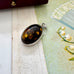 Silver pendant with embedded amber on a textured fabric background