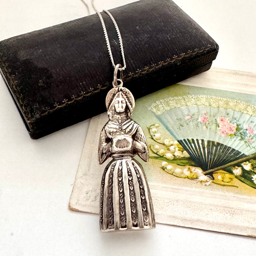 Vintage figural sterling silver needle cae necklace on an old jewellery box and with a vintage postcard
