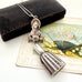 Vintage figural sterling silver needle cae necklace on an old jewellery box and with a vintage postcard
