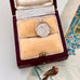 Vintage silver spinning "Good Luck" charm in a wooden box on a floral-patterned surface