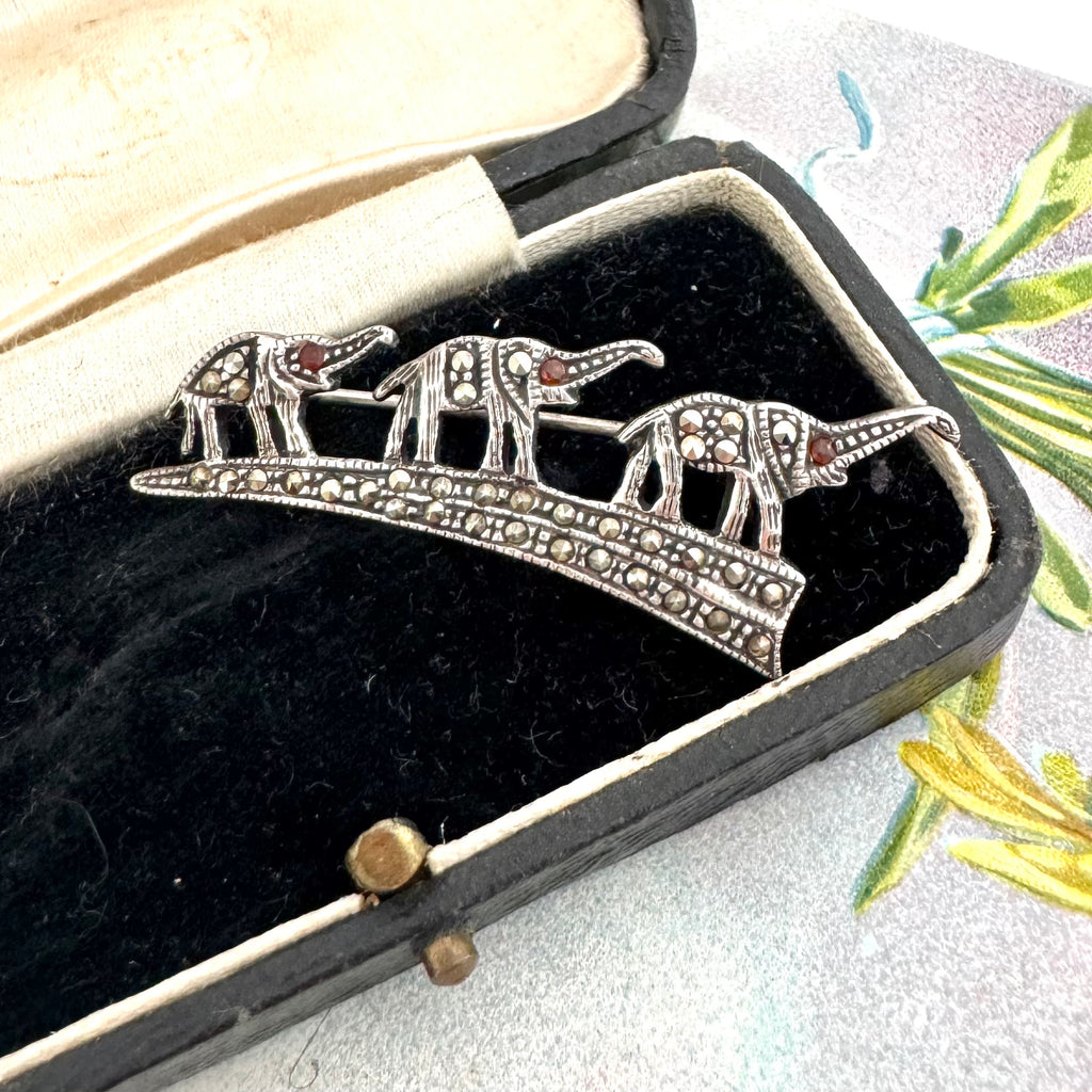 Vintage sterling silver three elephants in a row brooch in a decorative box with a floral background