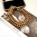 A vintage chunky gold-toned chain-link bracelet arranged on top of a vintage black-and-white photograph, with an open jewelry box partially visible behind it.