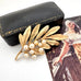 Trifari vintage gold leaf and pearl brooch with a black case and vintage illustration in the background