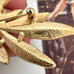 Gold feather-shaped brooch with 'Trifari' branding on a blurred background
