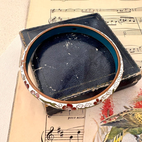 Vintage cloisonne bangle with floral design on a music sheet background