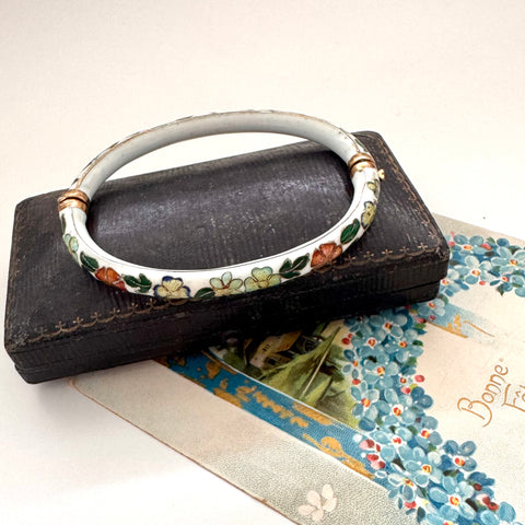 Decorative vintage cloisonne bracelet with floral patterns on a textured surface