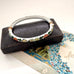 Decorative vintage cloisonne bracelet with floral patterns on a textured surface