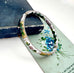 Vintage white cloisonne hinged bangle on an old jewellery box and with an old floral postcard