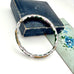 Vintage white cloisonne hinged bangle on an old jewellery box and with an old floral postcard