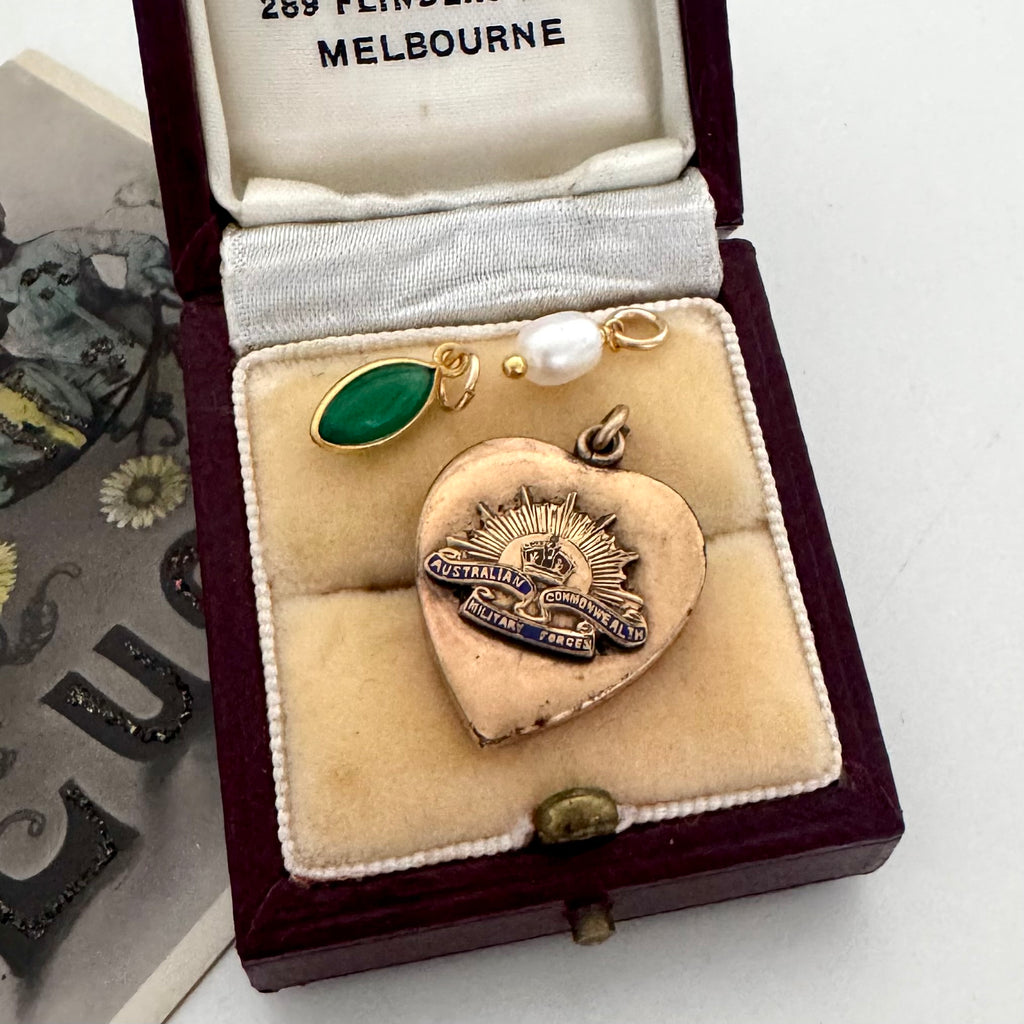 Vintage WW2 heart-shaped brooch with green stone and pearl charms  in a jewelry box labeled 'Melbourne'.