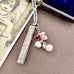 Vonk Jewellery antique 1885 button hook and pearl charm necklace on a brown background and with a vintage postcard and jewellery box