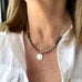 Image of a womans neck. She is wearing a Vonk Jewellery pearl and silver 1904 threepence necklace and a white linen shirt