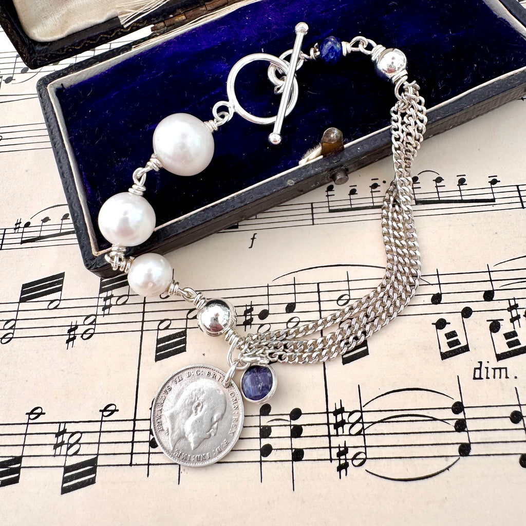 Vonk Jewellery 1905 threepence, pearl and sterling silver bracelet on a music manuscript and a vintage jewellery box