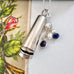 Vonk Jewellery 1922 silver cheroot case necklace with lapis and pearl charms on a white background with a vintage postcard 