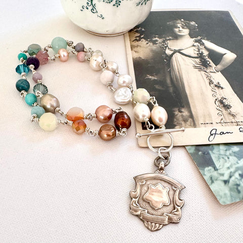 Vonk Jewellery 1935 watch fob, pearl and crystal necklace with a vintage postcard