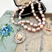 Vonk Jewellery pale pink pearl and vintage watch fob necklace on a vintage jewellery box and with vintage postcards.