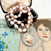 Vonk Jewellery pale pink pearl and vintage watch fob necklace on a vintage jewellery box and with vintage postcards.