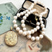 Vonk Jewellery rolled gold vintage locket and pearl necklace on a vintage jewellery box and vintage postcards