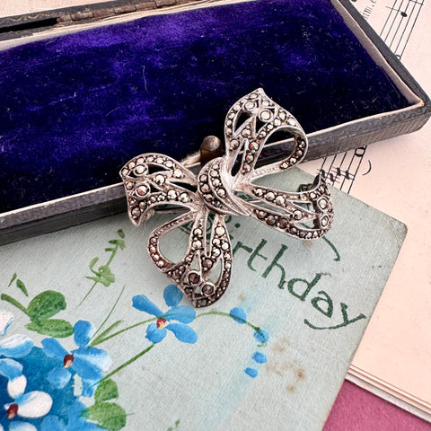 Vonk Jewellery silver marcasite bow brooch on a vintage postcard, sheet music and jewellery box