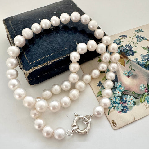 Pearl necklace with a silver clasp on a vintage book and card