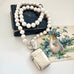 Pearl necklace with an antique silver vesta case  on a vintage book and postcard background