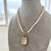 Pearl necklace with an antique silver vesta case pendant on a mannequin bust.