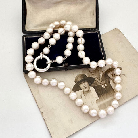 Pearl necklace on an open jewelry box with an old photograph underneath