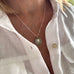 Image of a woman's neck. She is wearing a vonk Jewellery 1911 sixpence necklace and a white linen shirt