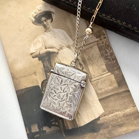 Vonk Jewellery antique sterling silver vesta case necklace on a vintage jewellery box and with a vintage postcard of a woman.