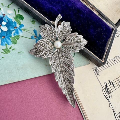 Vonk Jewellery large vintage silver metal marcasite leaf brooch on a vintage postcard, sheet music and jewellery box