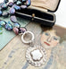 Vonk Jewellery peacock pearl and vintage silver watch fob necklace on 2 vintage postcards and with a vintage jewellery box