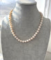 Pearl necklace on a gray mannequin bust with a blurred window background