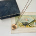 WW2 ACMF heart-shaped pendant  sweetheart locket on a chain against an old postcards with fan illustration