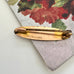 Back of antique gold lined  brooch on a floral-patterned fabric background