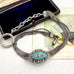 Antique French silver albertina chain with an oval turquoise and floral enamel centerpiece, displayed next to an open dark box on a light fabric surface.