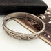 Silver bracelet with ivy leaf patterns on a white surface and with an old photograph