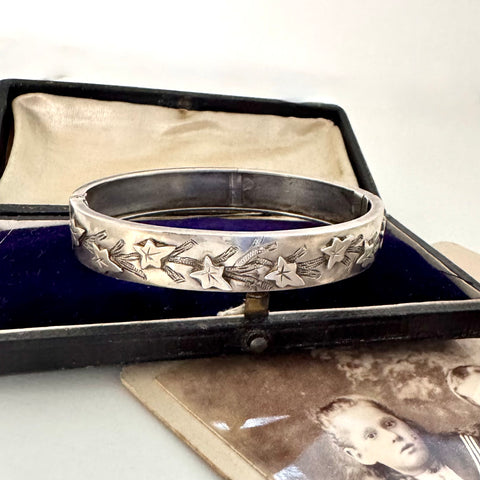 Silver bracelet with ivy leaf designs in an open jewelry box with an old photograph underneath.