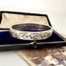 Silver bracelet with ivy leaf designs in an open jewelry box with an old photograph underneath.