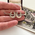 Antique silver horseshoe-shaped brooch held between fingers with a decorative card in the background.