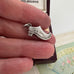 Antique silver shoe charm in a jewelry box on a textured surface