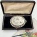 Silver Victorian aesthetic era locket in an open box on a white background